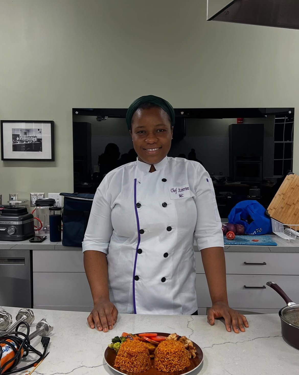 Chef Esther of Metheq Cuisine in her kitchen with plates of jollof rice